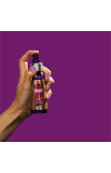 A gif of a hand spraying Aussie product on a purple background