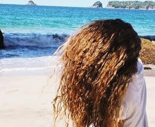 Picture of a woman with brown curly hair flipping her hair